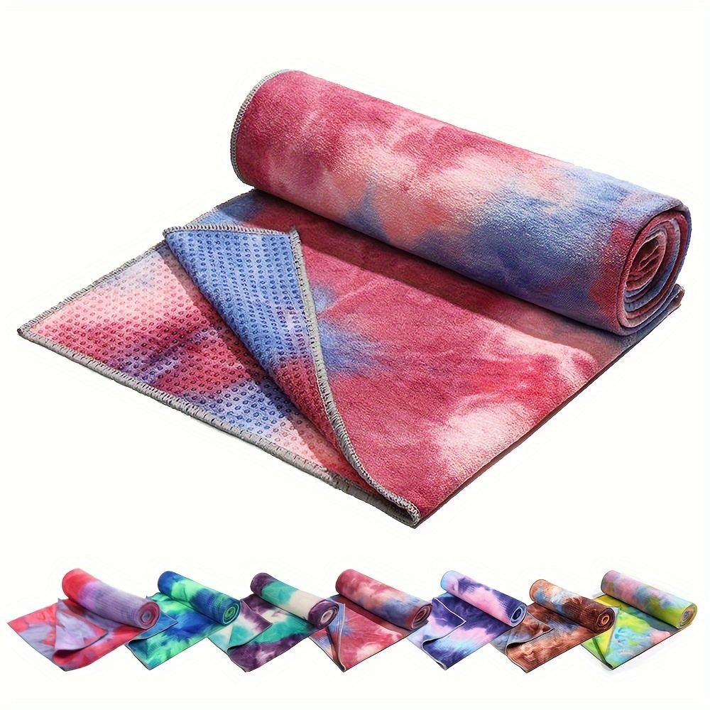 A sweat-absorbing non-slip yoga towel with its storage bag, laid over a mat for grip